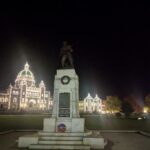 Stone memorial at night in front of a building with decorative lights