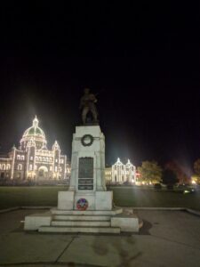 Stone memorial at night in front of a building with decorative lights